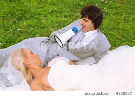 Beautiful young groom and bride wearing white dress lie on green Beautiful young groom and bride wearing white dress lie on green 4800297