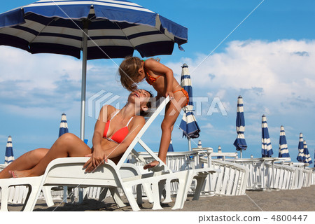 young mother lying on lounger under beach umbrella. little daugh young mother lying on lounger under beach umbrella. little daugh 4800447