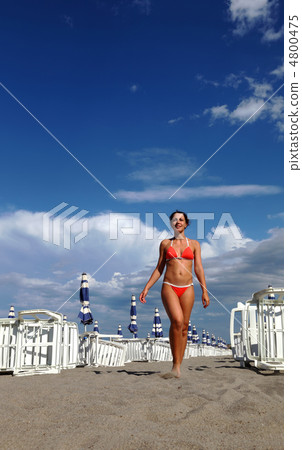 beautiful young woman in bathing suit goes on sand on beach. in 4800475