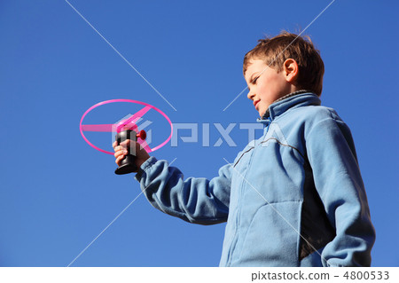 little boy in blue jacket plays with pink propeller. in backgrou little boy in blue jacket plays with pink propeller. in backgrou 4800533