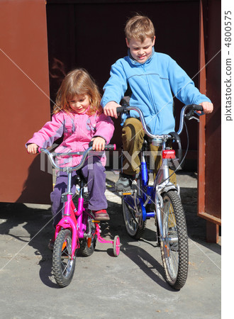 little brother and sister ride children's bicycles. girl in pink little brother and sister ride children's bicycles. girl in pink 4800575