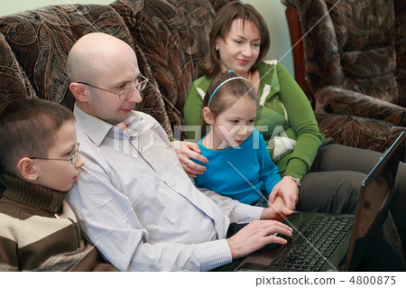 Father, mother, son and daughter sitting on couch and look at la Father, mother, son and daughter sitting on couch and look at la 4800875