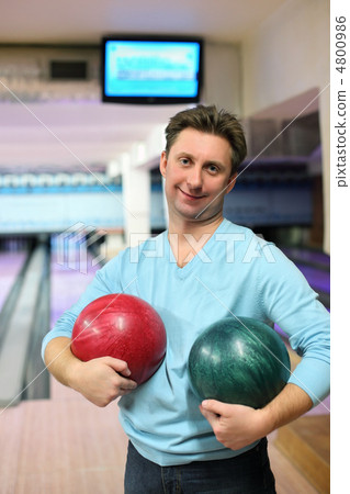 Man stands in club and holds two balls for bowling 4800986
