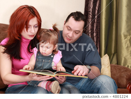 mother, father and little daughter in denim jumpsuit reads book mother, father and little daughter in denim jumpsuit reads book 4801224