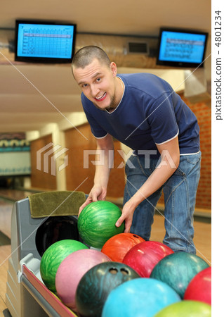 Youth bends over to automat  and takes  ball for playing bowling 4801234