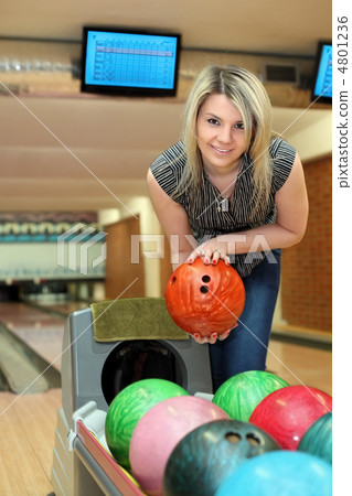 Girl takes two hands ball for playing bowling 4801236