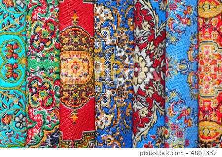Seven varicoloured carpets lie in rouleau on each other on verti 4801332