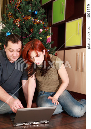 young wife and husband sitting on floor near Christmas tree and young wife and husband sitting on floor near Christmas tree and 4801559