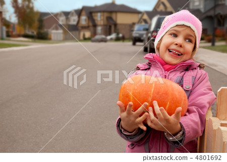 Smiling girl goes on road and bears pumpkin in hands 4801692