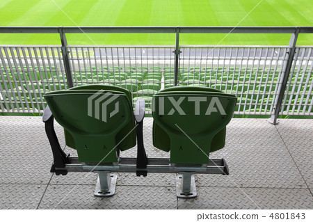 Two green plastic seats on tribune of large stadium, behind 4801843