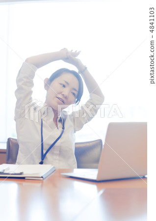 A woman watching a laptop while stretching at the window of backlight A woman watching a laptop while stretching at the window of backlight 4841103
