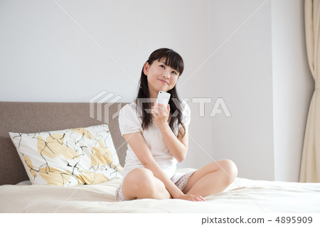 一名婦女在床上的看一個手機 一名婦女在床上的看一個手機 4895909