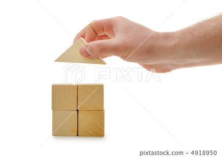 The hand establishes a toy roof on wooden cubes 4918950