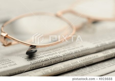 Eyeglasses lie on a pile of newspapers 4919888