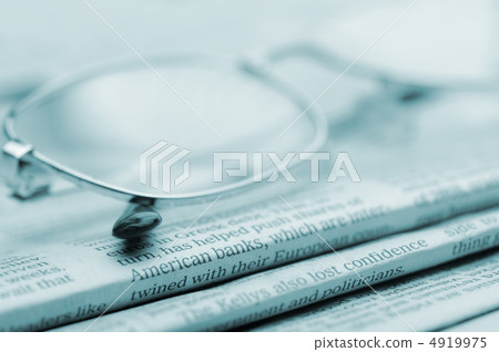 Eyeglasses lie on a pile of newspapers.Blue toned Eyeglasses lie on a pile of newspapers.Blue toned 4919975