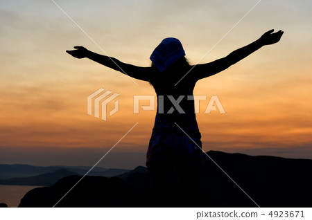 The woman on a mountain with open hands welcomes a decline. 4923671