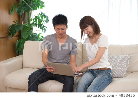 A couple looking at a computer in the living room A couple looking at a computer in the living room 4938436