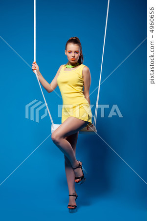 Sexy woman in yellow on swing with bright make-up 4960656