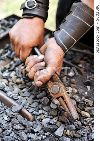 Detail of dirty hands holding pliers - blacksmith 5002090
