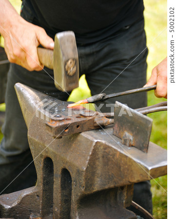 Blacksmith hammering hot steel on anvil 5002102