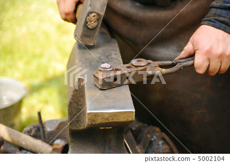 Blacksmith hammering hot steel on anvil 5002104