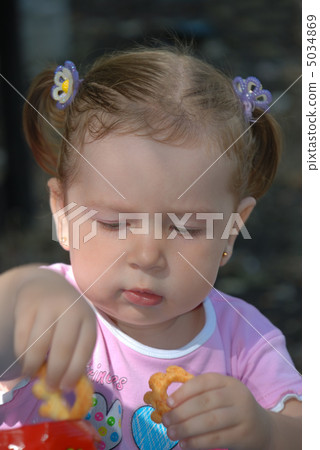 The girl taking cookie from a pack The girl taking cookie from a pack 5034869