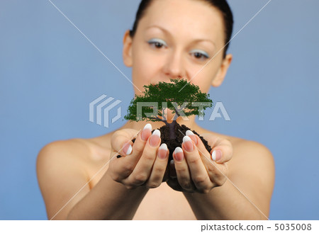 The woman holds in hands soil with a tree 5035008