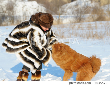 The woman in a mink fur coat plays with a dog The woman in a mink fur coat plays with a dog 5035570