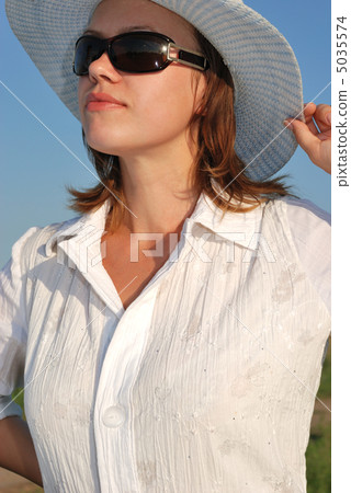 The woman in glasses and a hat on a background of the sky The woman in glasses and a hat on a background of the sky 5035574