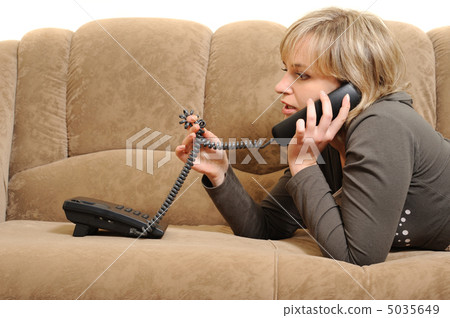 The woman speaking by phone on a sofa The woman speaking by phone on a sofa 5035649