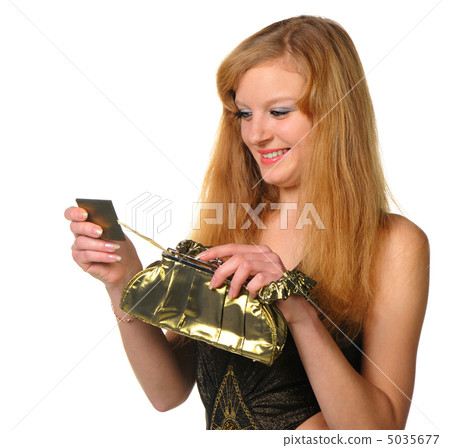 The woman in an evening dress is looked in a pocket mirror 5035677