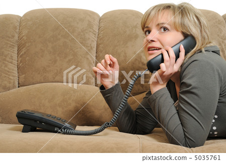 The woman speaking by phone on a sofa The woman speaking by phone on a sofa 5035761