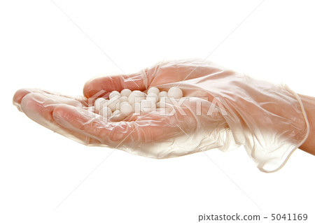 White pills on woman's palm in disposable glove 5041169