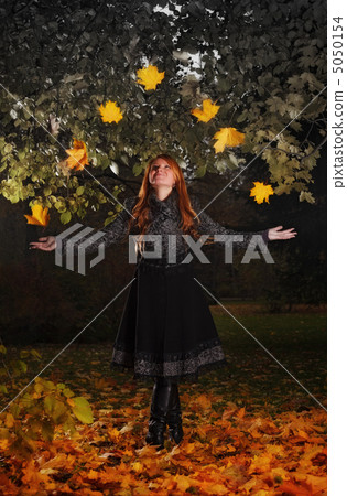 girl juggling leaves in autumn park 5050154