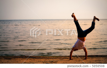 man doing handstand on beach 5050508