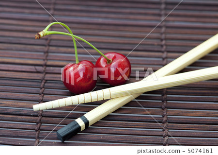 cherry and chopsticks on bamboo mat 5074161