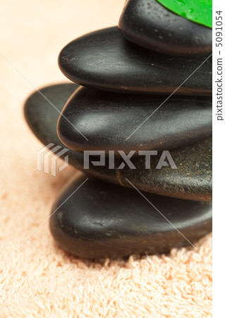 black spa stones with green leaf and a drop of water on the tow black spa stones with green leaf and a drop of water on the tow 5091054