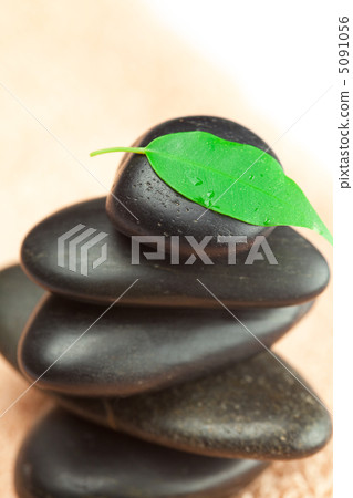black spa stones with green leaf and a drop of water on the tow black spa stones with green leaf and a drop of water on the tow 5091056
