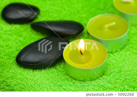 burning candle and spa black stones lying on the towel burning candle and spa black stones lying on the towel 5092268