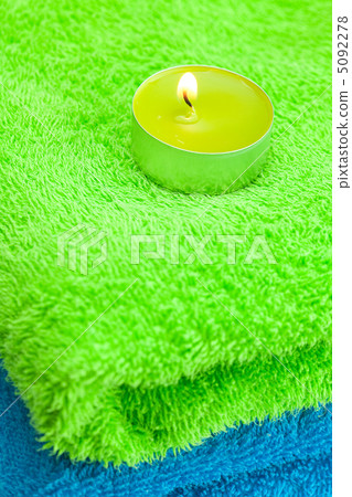 a burning candle lying on the towel a burning candle lying on the towel 5092278