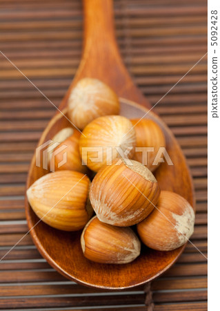 hazelnuts on a wooden spoon on a bamboo mat 5092428