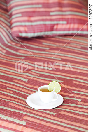 bed with two pillows, a cup of tea on the blanket 5097297