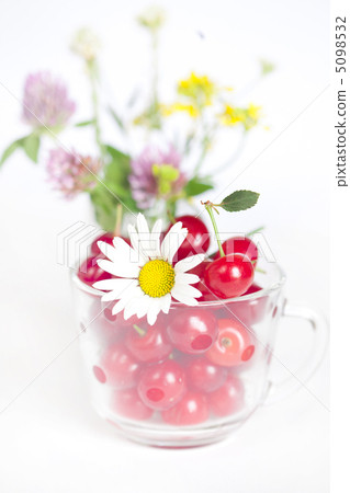 glass cup with cherries and a bouquet of wildflowers 5098532