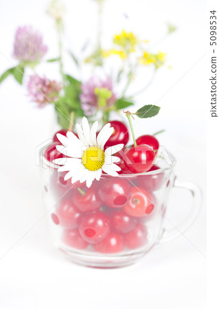 glass cup with cherries and a bouquet of wildflowers 5098534