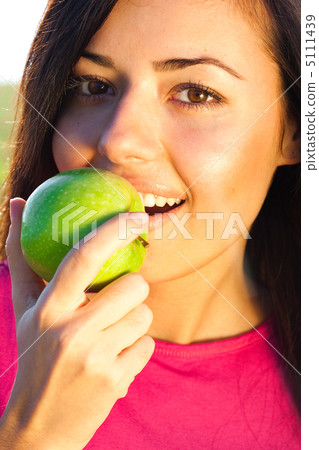 portrait of a beautiful young woman with apple  outdoor 5111439