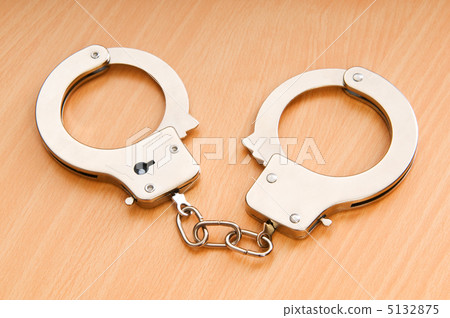 Metal handcuffs on the wooden background Metal handcuffs on the wooden background 5132875