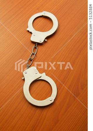 Metal handcuffs on the wooden background Metal handcuffs on the wooden background 5132884