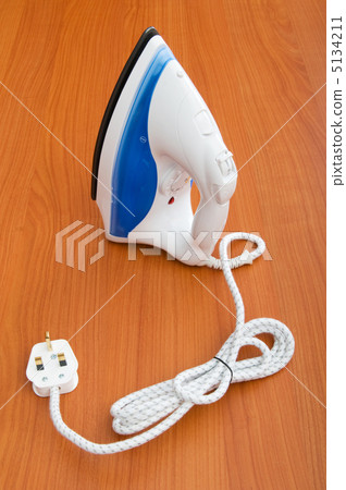 Modern electric iron on the wooden background Modern electric iron on the wooden background 5134211