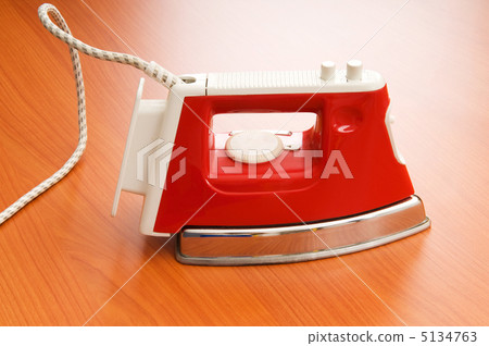 Modern electric iron on the wooden background Modern electric iron on the wooden background 5134763