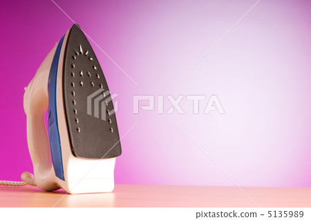 Modern electric iron against the colorful background 5135989